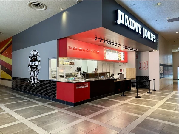 A Jimmy John's sandwich franchise in a mall, featuring a bold red and grey façade with promotional signs.